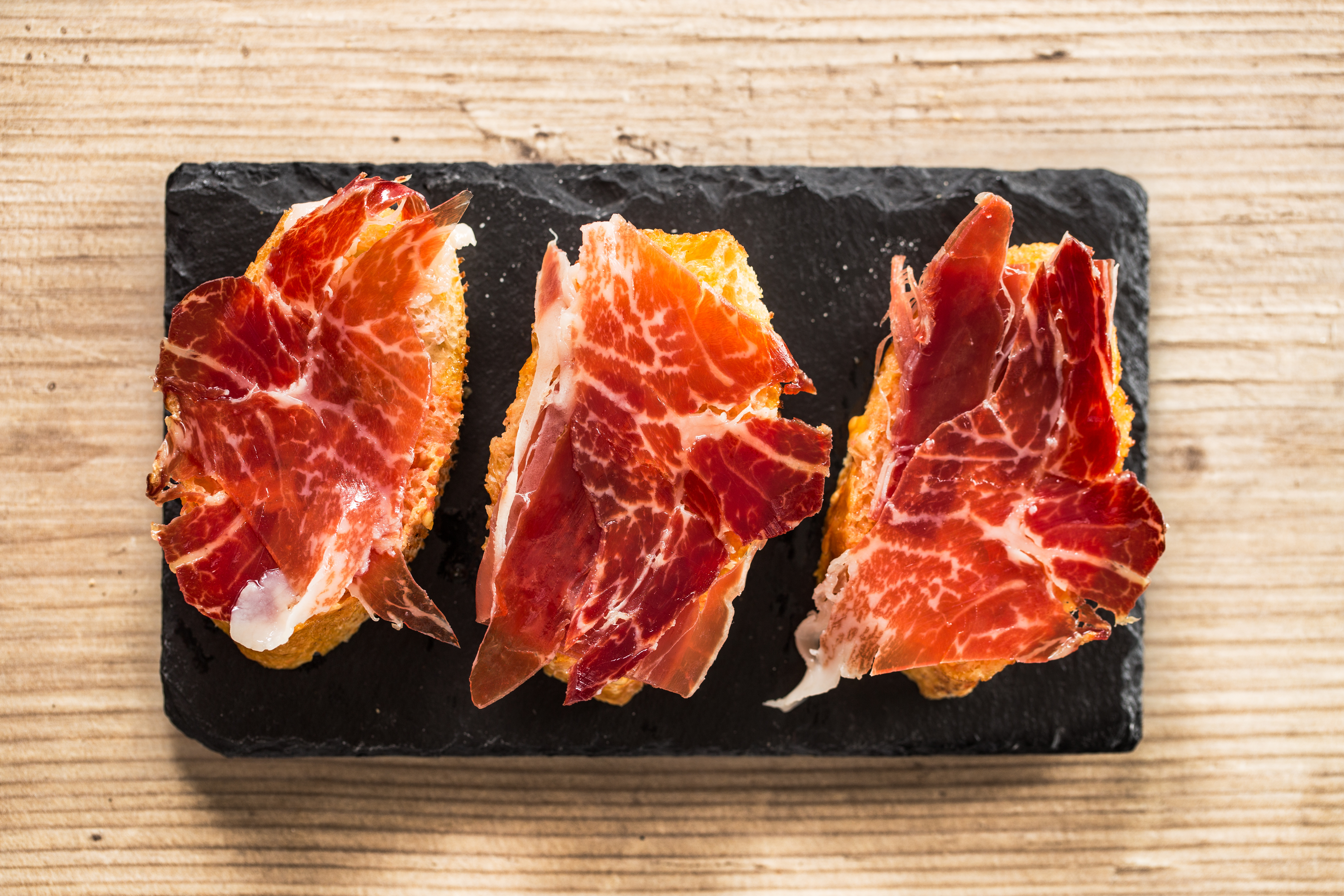 Jamon iberico tapas, top view on a wooden table
